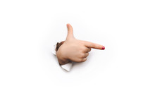 The Thumb And Forefinger Points To The Right Side. White Background And Place For Advertising With Copy Space. The Child's Hand Came Out Into The Torn Paper Hole.