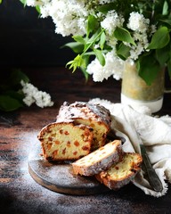 Wall Mural - Curd cake with raisins on a cutting board on a dark background with lilac flowers