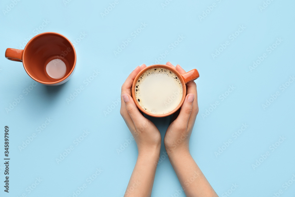 Female hands with cup of hot coffee on color background