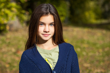 Wall Mural - Pretty brunette little girl posing in autumn park background