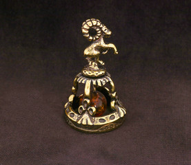 Wall Mural - Amber souvenir. A miniature metal bell in the form of a zodiac sign 