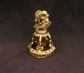 Wall Mural - Amber souvenir. A miniature metal bell in the form of a zodiac sign 