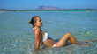 © Sylwia - Happy woman in bikini sunbathing by turquoise sea, Sardinia, Italy, La Cinta beach