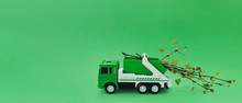 Green Toy Garbage Truck Carries Fresh Branches Of Trees With Leaves.Concept Of Waste Recycling,zero Waste.Concept Of Caring For The Environment.Copy Space For Text