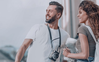 Poster - Young couple walking and looking at a guide while looking happy