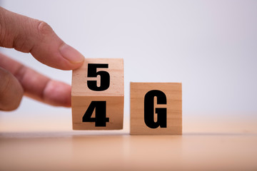 Hand flipping wooden cube for change 4G to 5G. Technology change transformation to high speed and internet of thing.