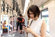 © Nattawat - Asian young short hair woman wearing glasses using  and looking her smartphone in train