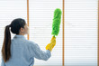 Young female spring cleaning house interior holding a duster for wiping dust dusting furniture at home.