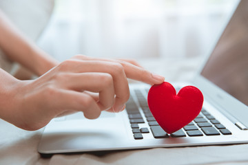 Hand touching red heart on laptop keyboard for flirt love chat or lover online text messenger for find date couple during stay home Coronavirus pandemic situation