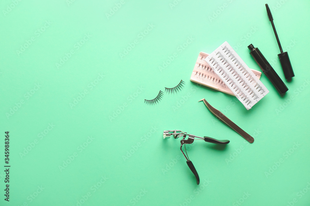Mascara, eyelash extensions, tweezers and curler on color background