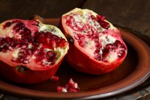 Two Halves Of A Pomegranate Fruit On A Plate.  The Pomegranate Fruit Split Open In With Seeds Visible