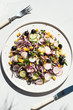 Photo of a fresh spring salad on a white porcelain plate from vegetable mix of ingredients  on a white rustic background sunlight with leaf shadows