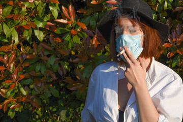 Girl with surgical face protection mask smoking a cigarette.