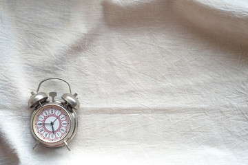 Clock alarm clock on a white cloth background of the table