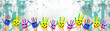 Many brightly painted children's hands with smileys, isolated on white background banner panorama with speckled spotted turquoise paint blobs, with space for text