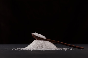 Glutamic acid monosodium salt in a wooden spoon on a dark background. Msg. Food additive E621. Flavor seasoning for enhancing food impressions. The additive is used in the food industry