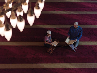 father and son in mosque praying and reading holly book quran together