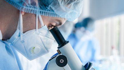 Wall Mural - biochemical research scientist working with microscope for coronavirus vaccine development in pharma
