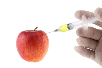 Injection into an apple. A hand in a medical glove with a syringe on a White background. Genetic modified foods. Injection of GMOs.