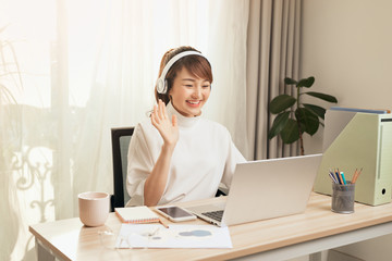 Fototapete - Beautiful Asian woman calling video by laptop at working place home.