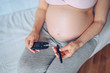 © Алина Троева - Diabetes checking blood sugar. Woman using lancelet and digital glucometer at home. Medicine, diet, health care concept - pregnant woman big belly checking body glucose level. Pregnancy, motherhood