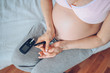 © Алина Троева - Diabetes checking blood sugar. Woman using lancelet and digital glucometer at home. Medicine, diet, health care concept - pregnant woman big belly checking body glucose level. Pregnancy, motherhood