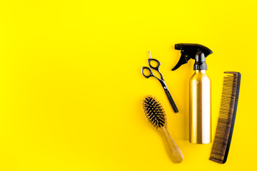 Wall Mural - Hairdressing instruments. Combs, scissors and spray on yellow desk from above frame space for text