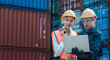 Technician or engineer with yellow helmet use walkie-talkie to contact with co-worker in cargo container shipping yard. Industry of logistics network concept.