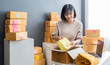 © sutthinon602 - Startup small business owner working with computer at workplace. Freelance  woman seller check product order. Packing goods for delivery to customer. Online selling. E-commerce. Online Shopping