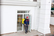 © Angelov - Delivery Man standing with yellow thermo backpack for food delivery near the entrance home with empty space to copy paste