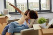 © Syda Productions - moving, people, repair and real estate concept - happy african american couple with cardboard boxes sitting on sofa at new home