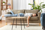 Fototapeta  - people, boredom and depression concept - bored or lazy young woman lying on sofa at home