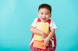 © sorapop - Back to school concept. Portrait Asian happy funny cute little child boy smiling and laugh hug books, studio shot isolated blue background. Kid from preschool kindergarten with school bag education