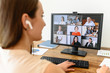 © Vadim Pastuh - Video call, video meeting. A young woman connect with a many employees together via video, she sits at office space and looks at webcam, rear view