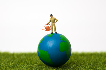 miniature farmer standing on globe with white background