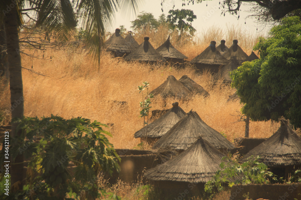 tradycyjne afrykańskie okrągłe chaty pokryte słomą wśród suchych traw - obrazy, fototapety, plakaty 