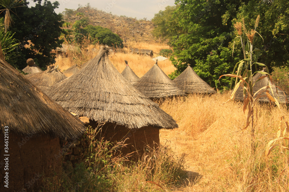 tradycyjne afrykańskie okrągłe chaty pokryte słomą wśród suchych traw - obrazy, fototapety, plakaty 