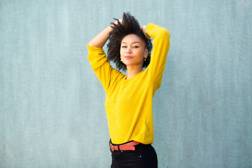 Wall Mural - african american female fashion model with hands in hair by green background