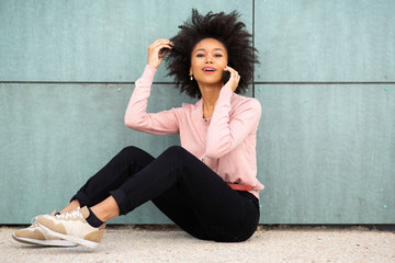 Wall Mural - african american woman sitting on floor outside talking with mobile phone