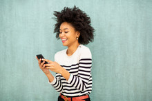 Smiling Young African American Woman Looking At Phone Text Message By Green Background