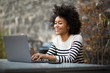© mimagephotos - smiling young african american woman using laptop computer