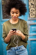 © mimagephotos - attractive young black woman with cellphone and earphones