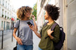 © mimagephotos - happy female black friends walking in city with mobile phone listening to music with earphones