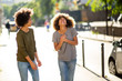© mimagephotos - two black female friends walking and laughing in city