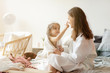 © deniskomarov - Daughter and mother in playful mood sitting on bed  in bedroom after shower.