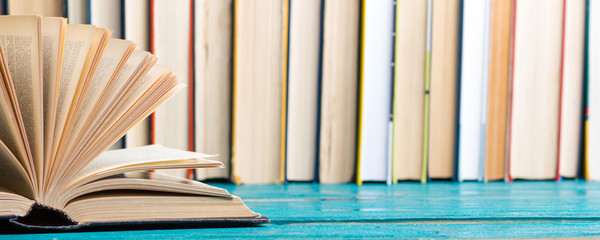 Composition with vintage old hardback books, diary, fanned pages on wooden deck table and red background. Books stacking. Back to school. Copy Space. Education background.