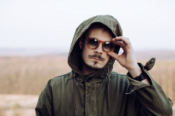 Wall Mural - Portrait of a stylish man with a mustache and beard in sunglasses in the mountains