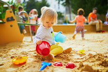 Adorable Little Girl On Playground In Sandpit