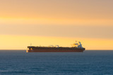 Fototapeta  - Cargo ship at sunset in the coasts of Chile outside the port of Valparaiso.
