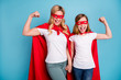© deagreez - Photo of beautiful mom lady little daughter spend time together carnival super hero costumes showing strength muscles wear s-shirts red coat masks isolated blue color background